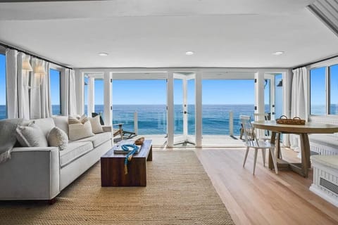 The living room features breathtaking oceanfront views, a beamed ceiling, and a cozy fireplace, creating a tranquil and inviting space.