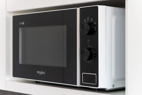 A microwave neatly placed on a white countertop, showcasing a modern and functional appliance setup.