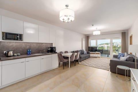 A combined kitchen and dining area with white cabinetry, a dining table, and open access to the living room, emphasizing an open-plan design.