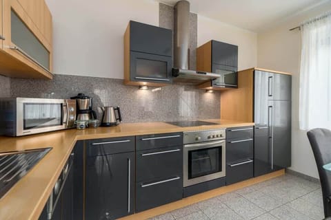 A modern kitchen with dark cabinets, a wooden countertop, and integrated appliances, blending style and functionality.