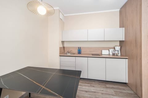 A kitchen and dining area with white cabinetry, wooden details, and a black dining table, combining elegance with practicality.