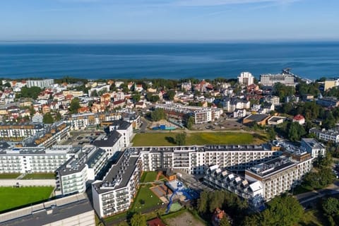 An aerial view of a residential area near the sea, showcasing modern buildings and green spaces.