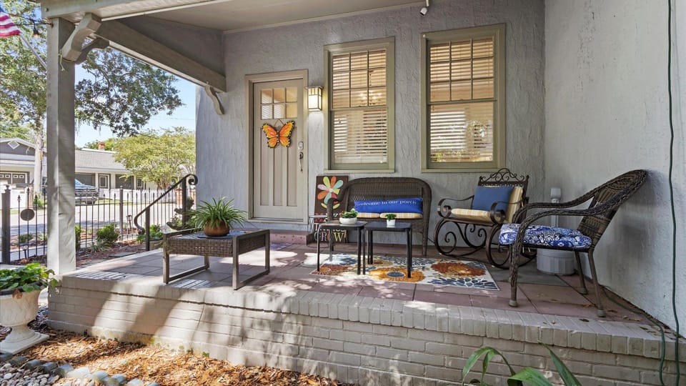Charming Front Porch: Unwind on the spacious porch with vibrant decor and lush greenery!

